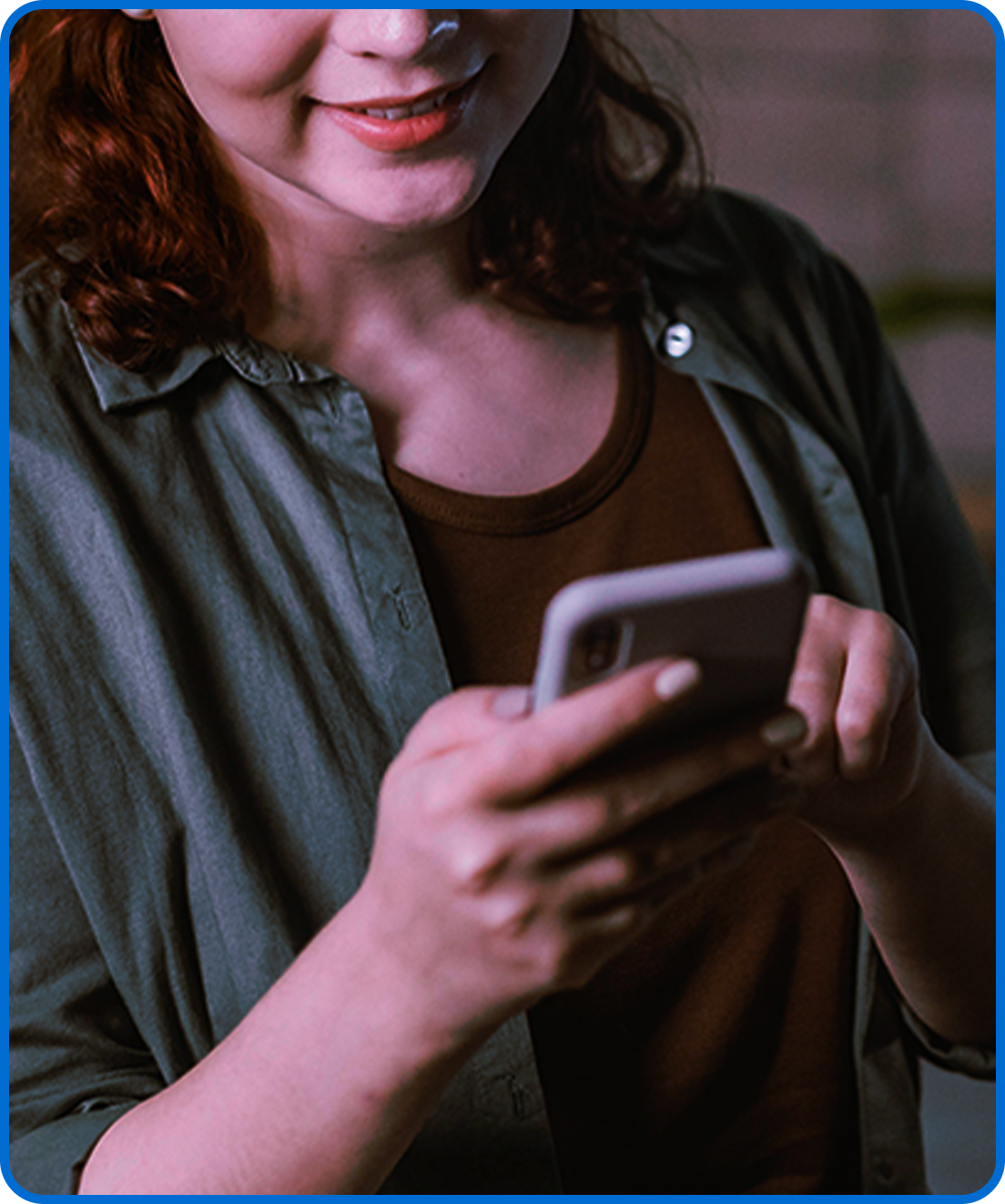 Colaboradora sorrindo enquanto usa o celular